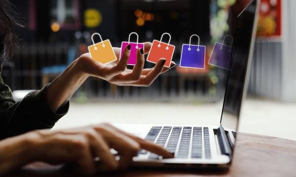 Αγορά από laptop και πολύχρωμες μικρές σακούλες με ψώνια.